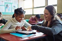 Photo of a teacher working with a student using a tablet computer